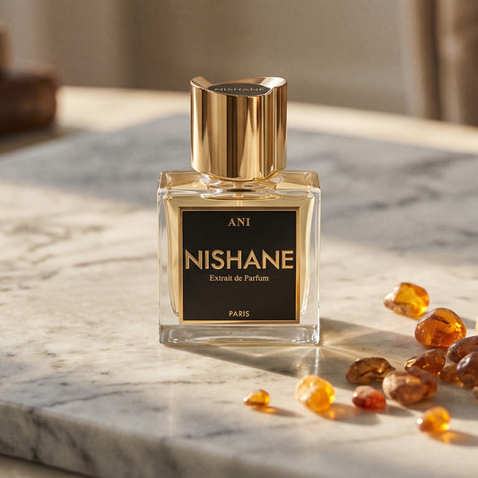 Nishane Ani Extrait de Parfum on cream stone with a scatter of honey-colored ambergris flakes
