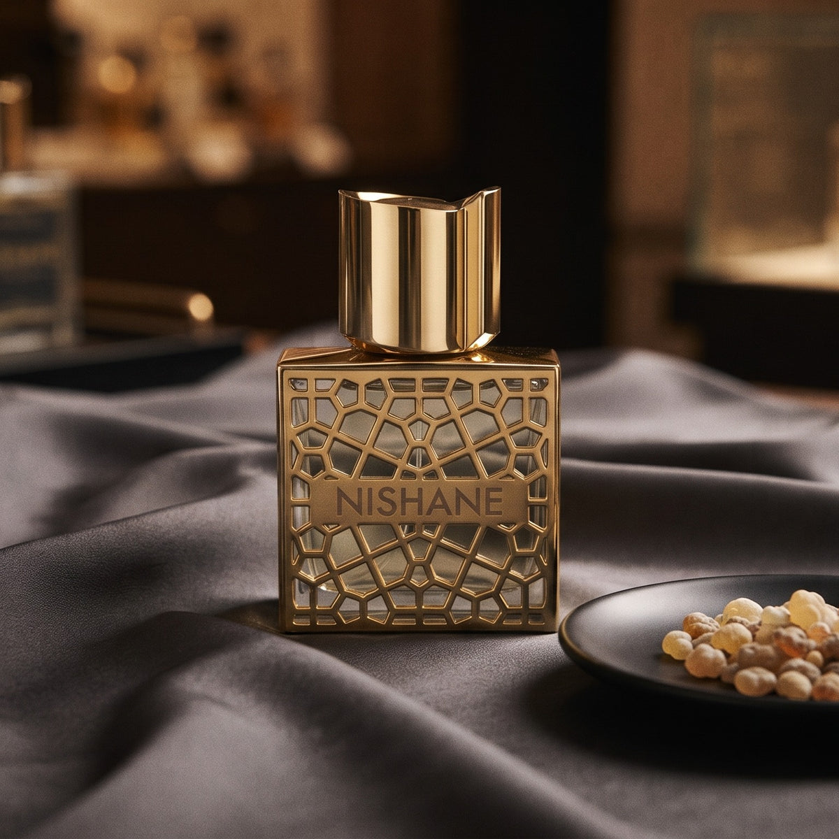 Nishane Hacivat Oud Extrait de Parfum on charcoal silk with frankincense resin granules in a small saucer