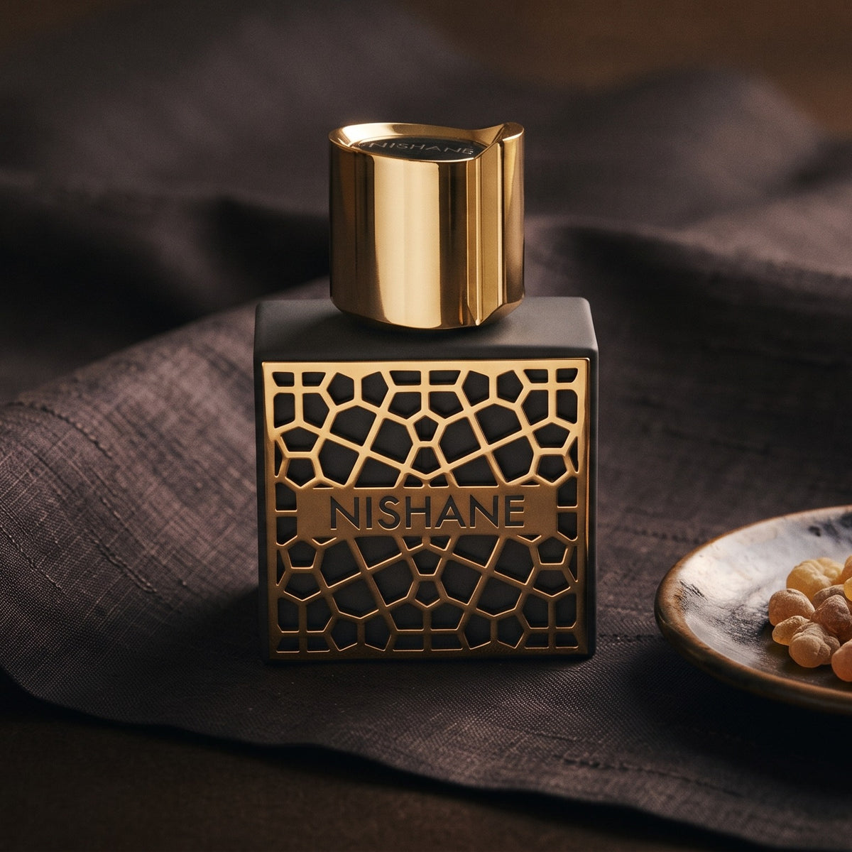 Nishane Mana Extrait de Parfum on charcoal silk with frankincense resin granules in a small saucer