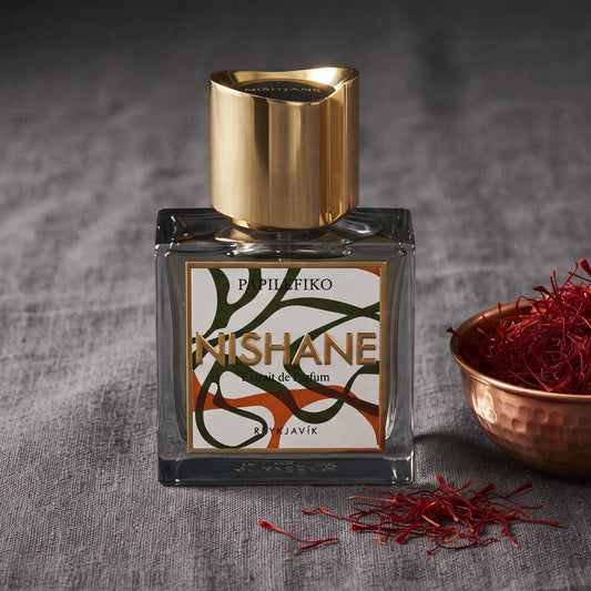Nishane Papilefiko Extrait de Parfum on charcoal linen with a small copper bowl of saffron threads