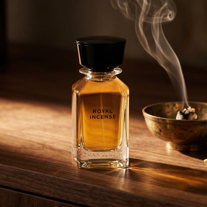 Oman Luxury Royal Incense EDP on black marble with a tall brass incense holder, smoke trailing diagonally