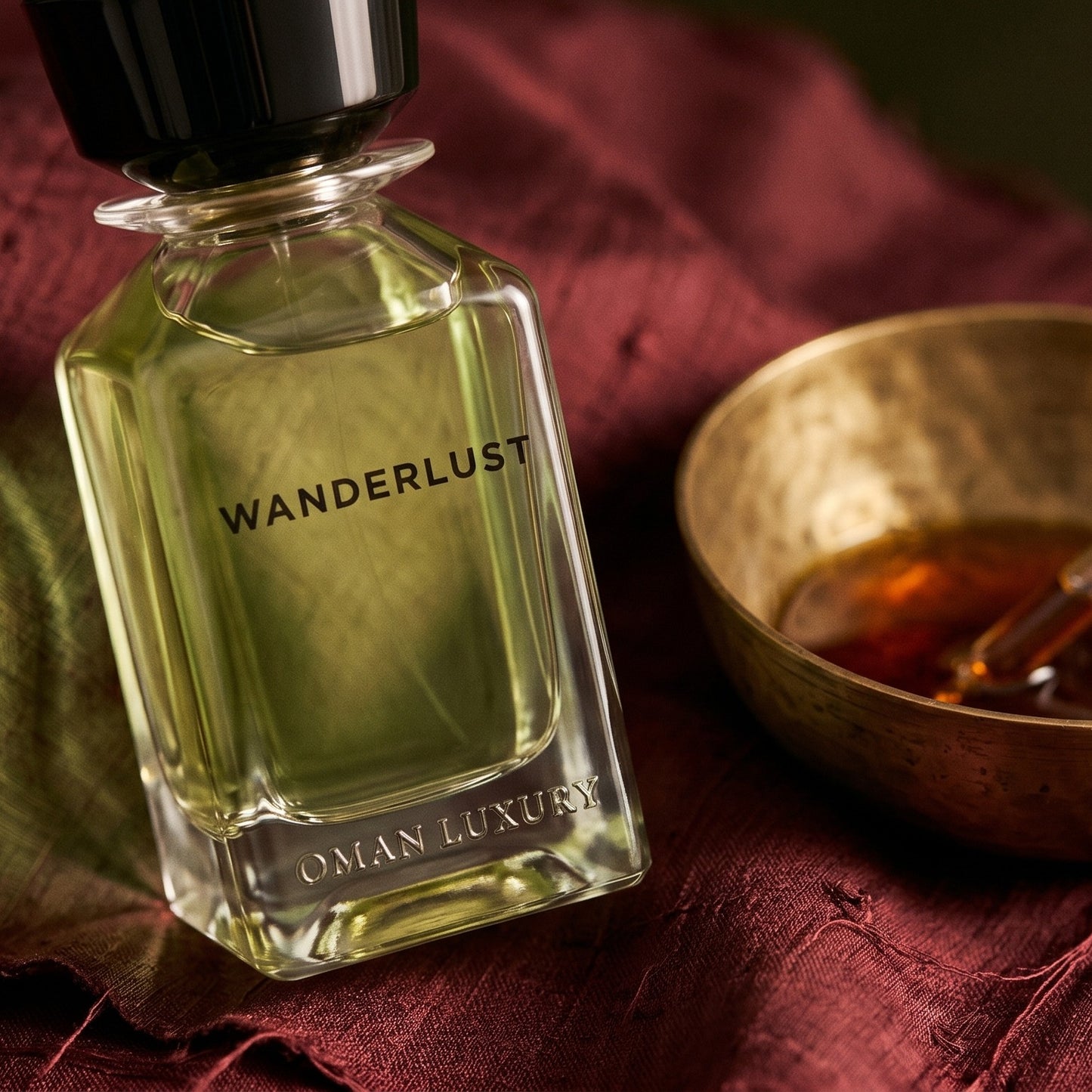 Oman Luxury Wanderlust EDP on raw silk of oxblood color with a brass bowl of ambergris tincture