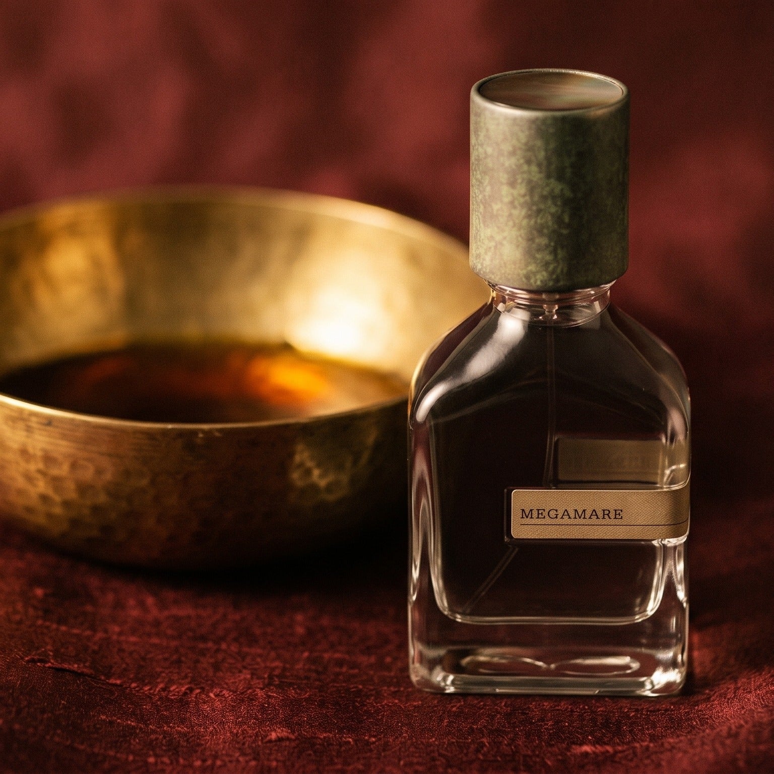 Orto Parisi Megamare on amber-toned satin with a gold-rim ceramic dish of labdanum