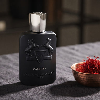 Parfums de Marly Carlisle EDP on charcoal linen with a small copper bowl of saffron threads