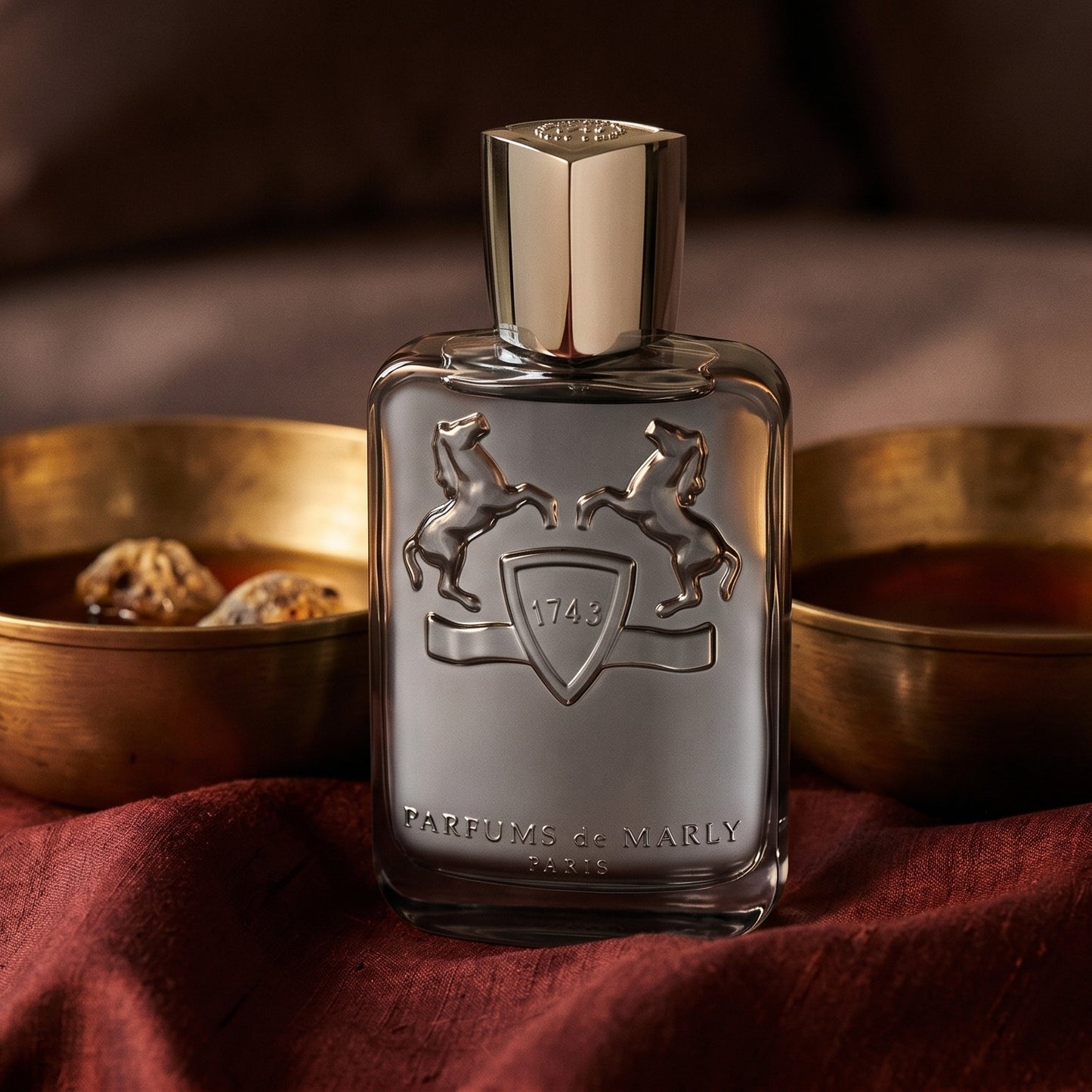 Parfums de Marly Castley EDP on burnt-orange raw silk with a brass vial of frankincense oil