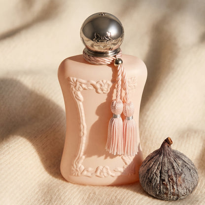Parfums de Marly Delina EDP on beige wool with a halved dried date and a few almonds