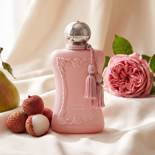 Parfums de Marly Delina Exclusif Parfum on cream silk with a ripe pear beside fresh lychees and a Damask rose