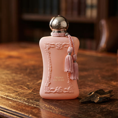 Parfums de Marly Delina Exclusif Parfum on aged library leather with a small stack of resinous wood splinters