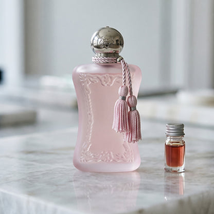 Parfums de Marly Delina la Rosee on cream-toned stone with a glass pipette of rose absolute