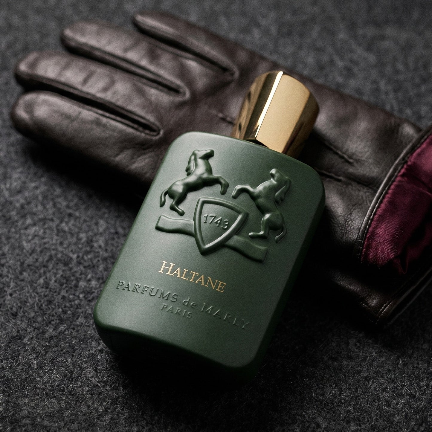 Parfums de Marly Haltane on oxblood leather footstool with a cashmere throw gathered behind