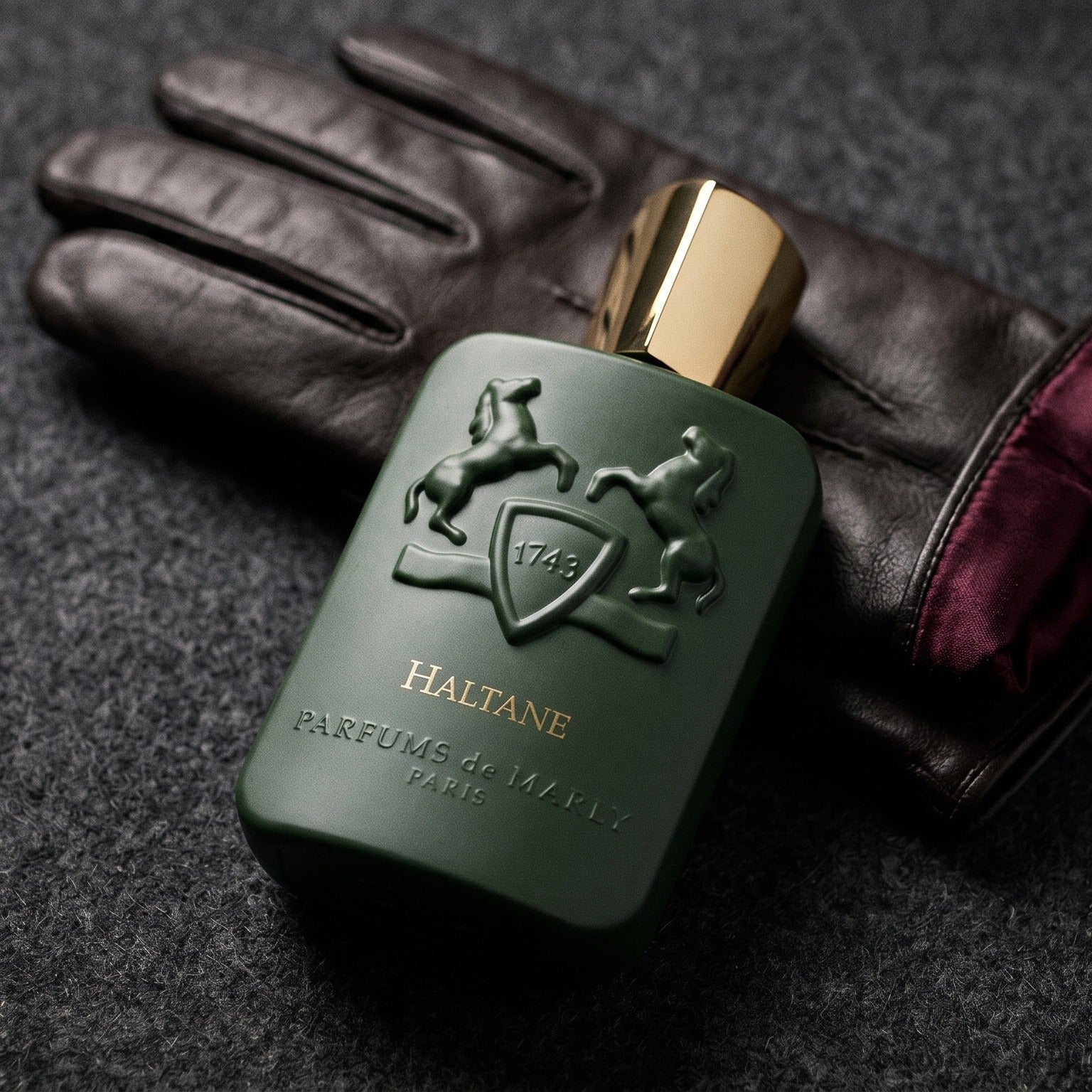 Parfums de Marly Haltane on oxblood leather footstool with a cashmere throw gathered behind
