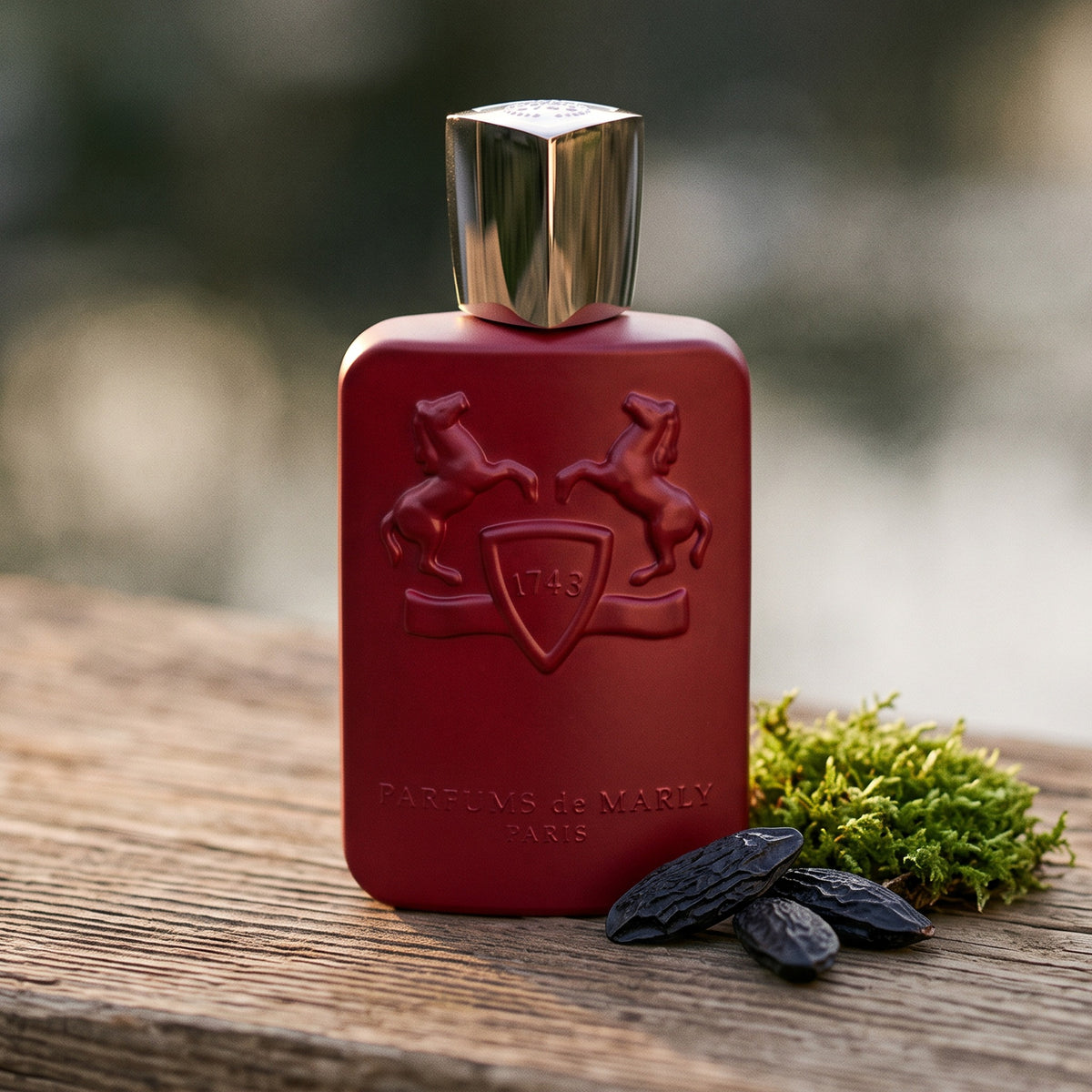 Parfums de Marly Kalan EDP on cedar board with a few tonka beans beside a tuft of green moss