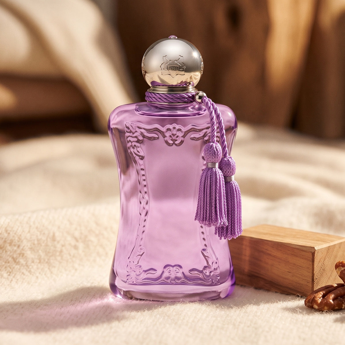 Parfums de Marly Palatine on cream cashmere with a small sandalwood block beside a few pieces of praline