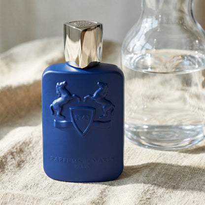 Parfums de Marly Percival EDP on bleached canvas with a decanter of infused orange water