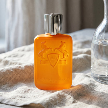Parfums de Marly Perseus on pale flax fabric with a glass jar of bergamot essence