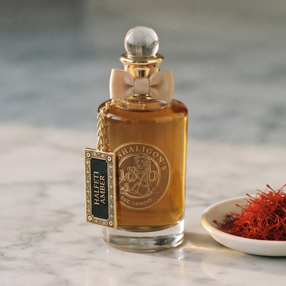 Penhaligon's Halfeti Amber EDP - Dubai Exclusive on pale grey marble with a small white ceramic dish of crimson saffron threads