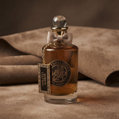 Penhaligon's Halfeti Amber EDP - Dubai Exclusive on warm taupe suede with a folded suede swatch resting just behind the bottle