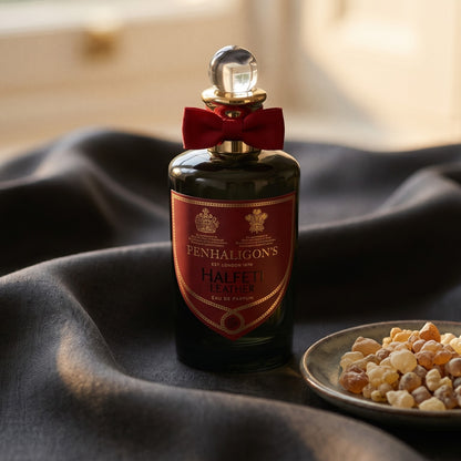 Penhaligon's Halfeti Leather EDP on burnt-orange silk with smoldering agarwood on a stone dish
