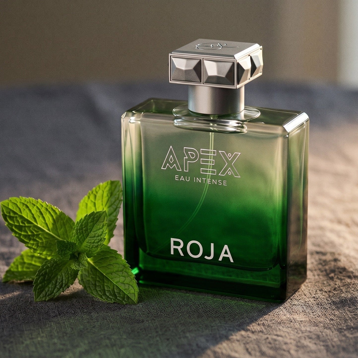 Roja Apex Eau Intense EDP on charcoal linen with a sprig of mint