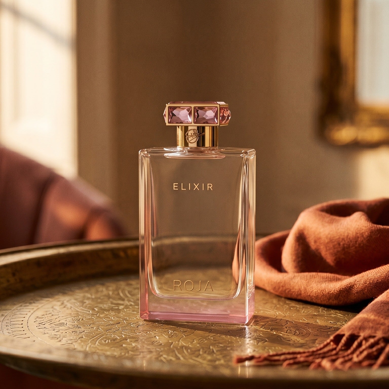 Roja Elixir Pour Femme EDP on aged brass tray with a folded pashmina in rust tone