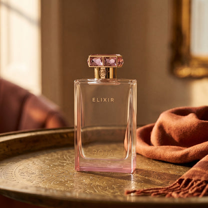 Roja Elixir Pour Femme EDP on aged brass tray with a folded pashmina in rust tone