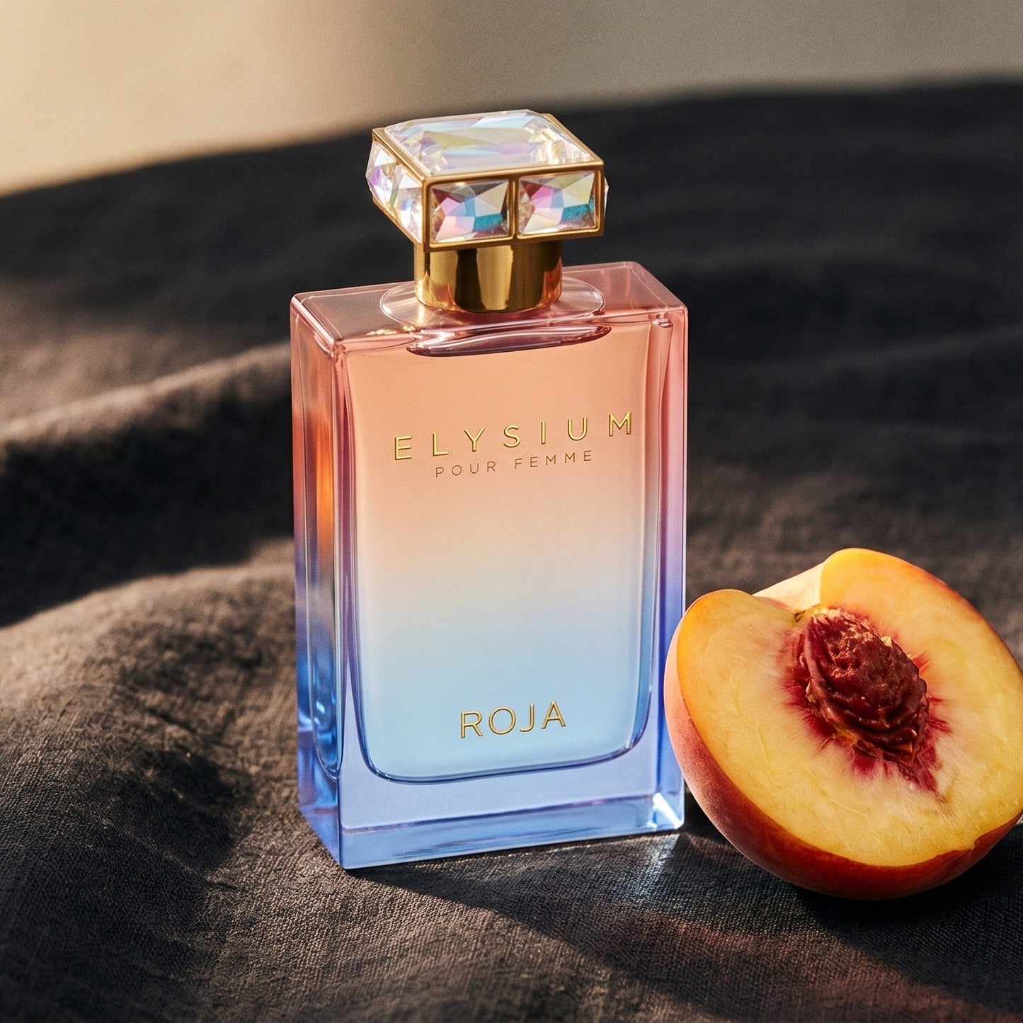 Roja Elysium Pour Femme EDP on charcoal linen with a halved peach