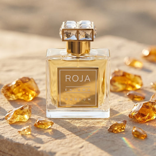 Roja Enigma Pour Femme Parfum on pale sandstone with golden amber shards catching the light