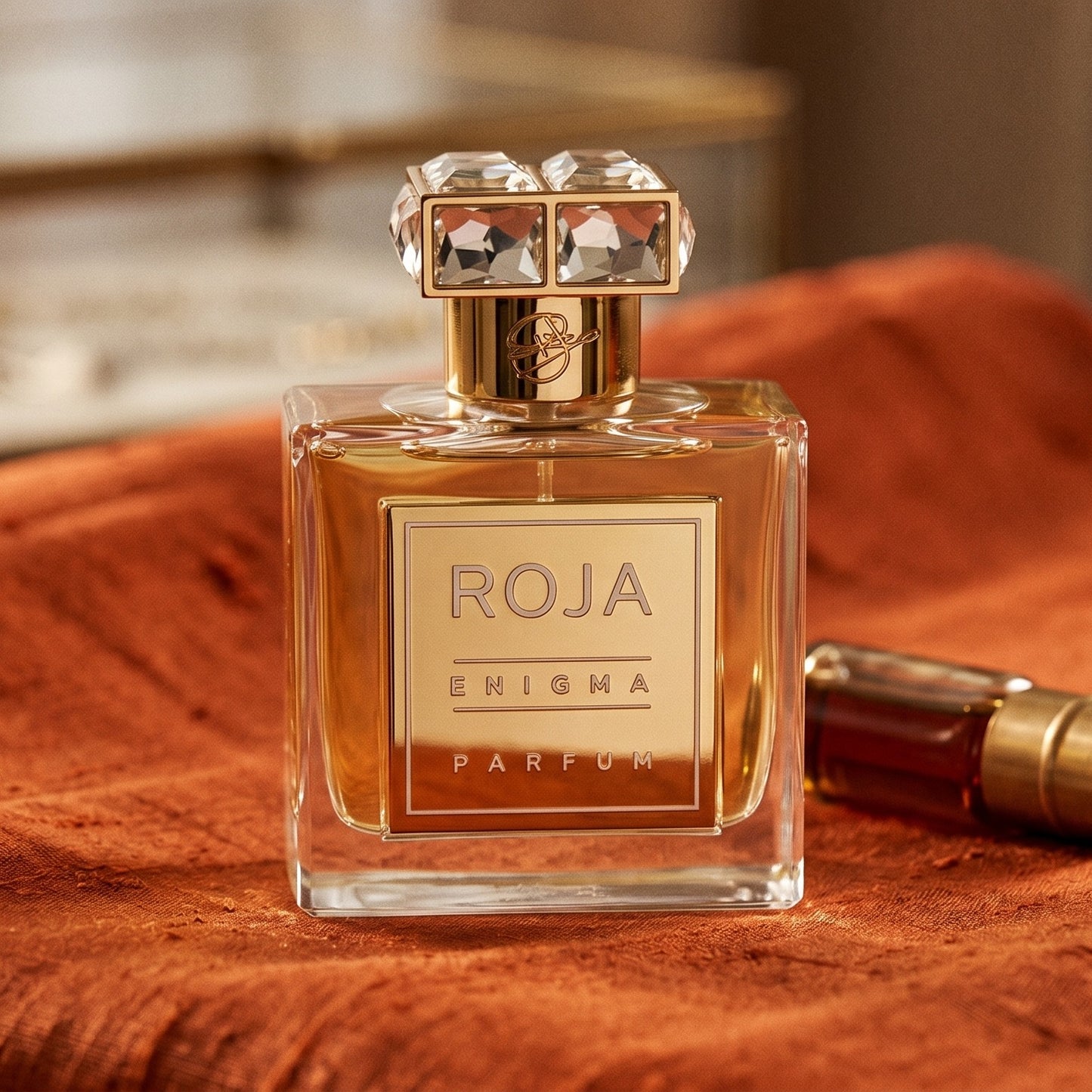 Roja Enigma Pour Femme Parfum on burnt-orange raw silk with a brass vial of frankincense oil
