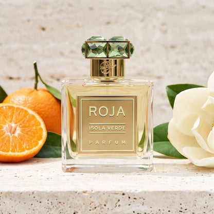 Roja Isola Verde Parfum on pale travertine with halved clementines beside a magnolia flower
