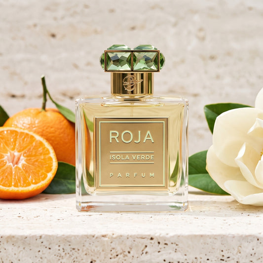 Roja Isola Verde Parfum on pale travertine with halved clementines beside a magnolia flower