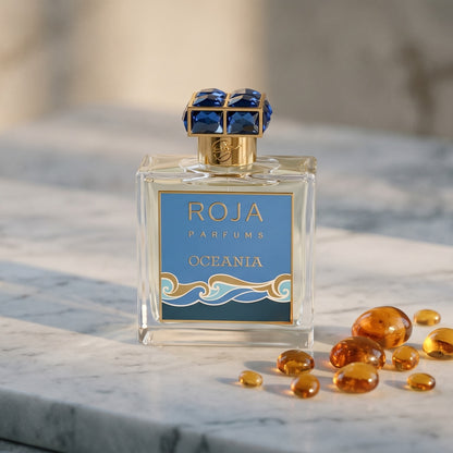 Roja Oceania EDP on pale grey marble with amber resin beads scattered to one side