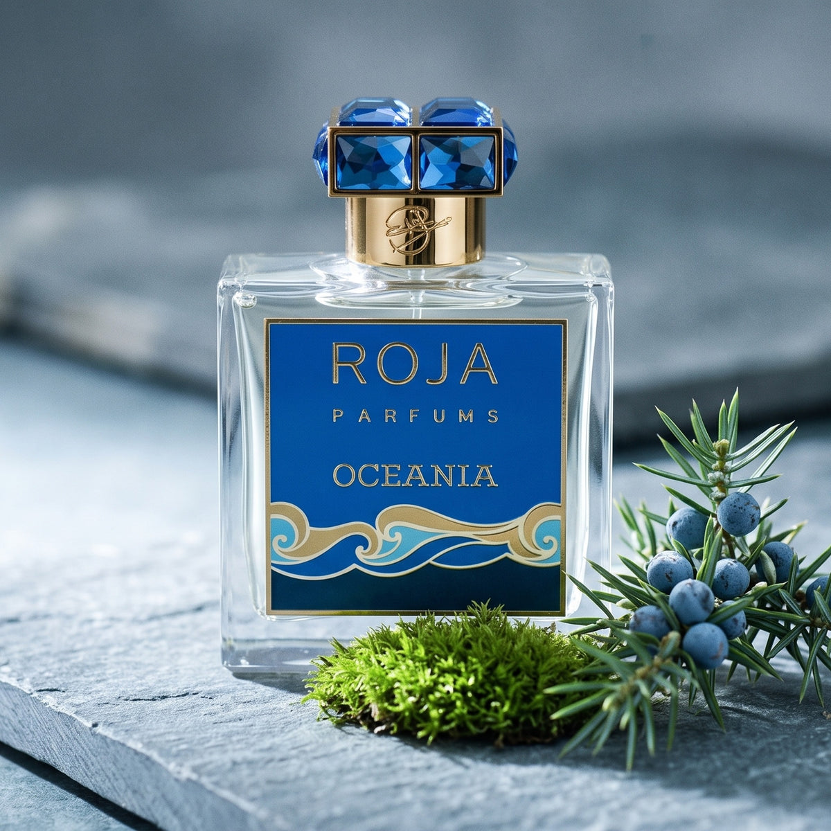 Roja Oceania EDP on grey stone slab with a tuft of green moss beside a sprig of juniper