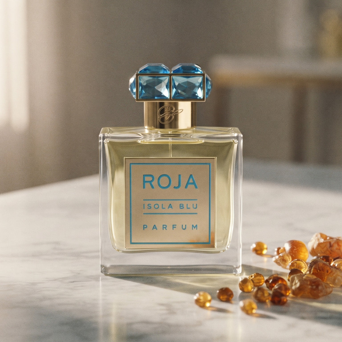Roja Isola Blu Parfum on pale grey marble with amber resin beads scattered to one side