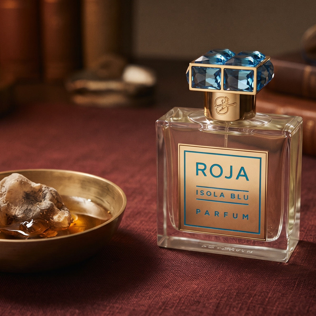 Roja Isola Blu Parfum on raw silk of oxblood color with a brass bowl with ambergris tincture