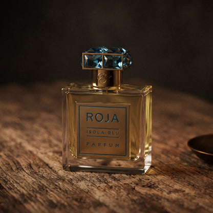 Roja Isola Blu Parfum on aged teak with a candle burning gently to frame-right