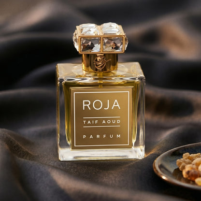 Roja Taif Aoud Parfum on charcoal raw silk with amber resin pieces near the bottle base