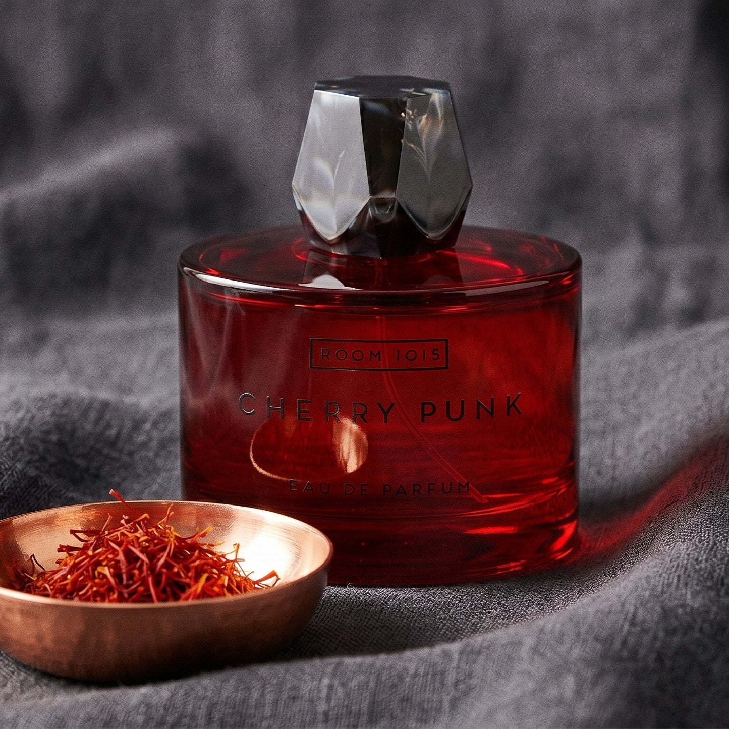 Room 1015 Cherry Punk EDP on obsidian surface with a brass bowl of red saffron stamens