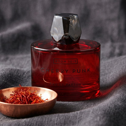 Room 1015 Cherry Punk EDP on obsidian surface with a brass bowl of red saffron stamens