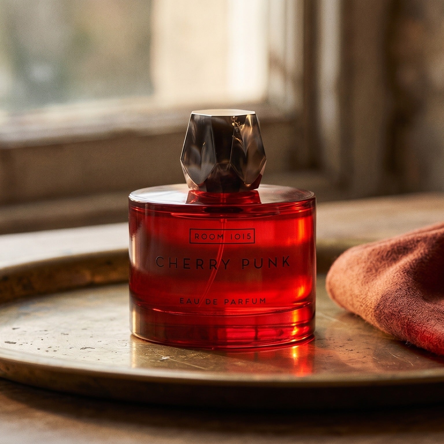 Room 1015 Cherry Punk EDP on patinated bronze tray with a folded shawl in deep saffron