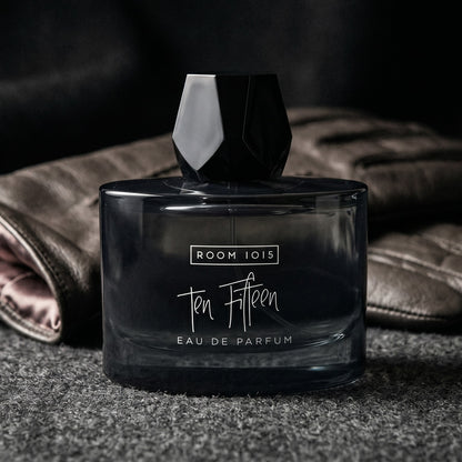 Room 1015 Ten Fifteen EDP on black suede surface with a folded pocket square beside the base