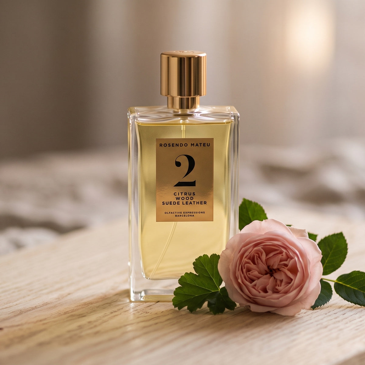 Rosendo Mateu No. 2 EDP on pale sandalwood board with a single rose with a few geranium leaves
