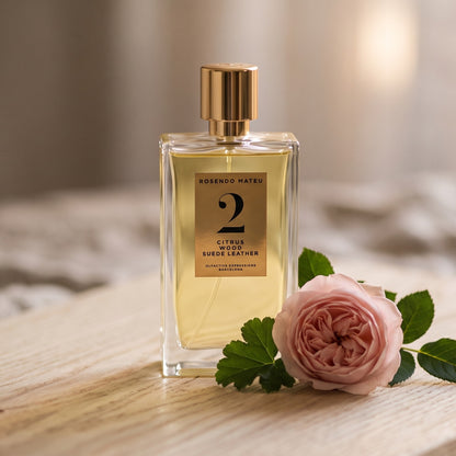 Rosendo Mateu No. 2 EDP on pale sandalwood board with a single rose with a few geranium leaves