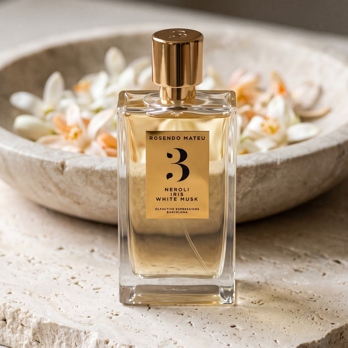 Rosendo Mateu No. 3 EDP on pale stone with orange-blossom petals in a shallow bowl