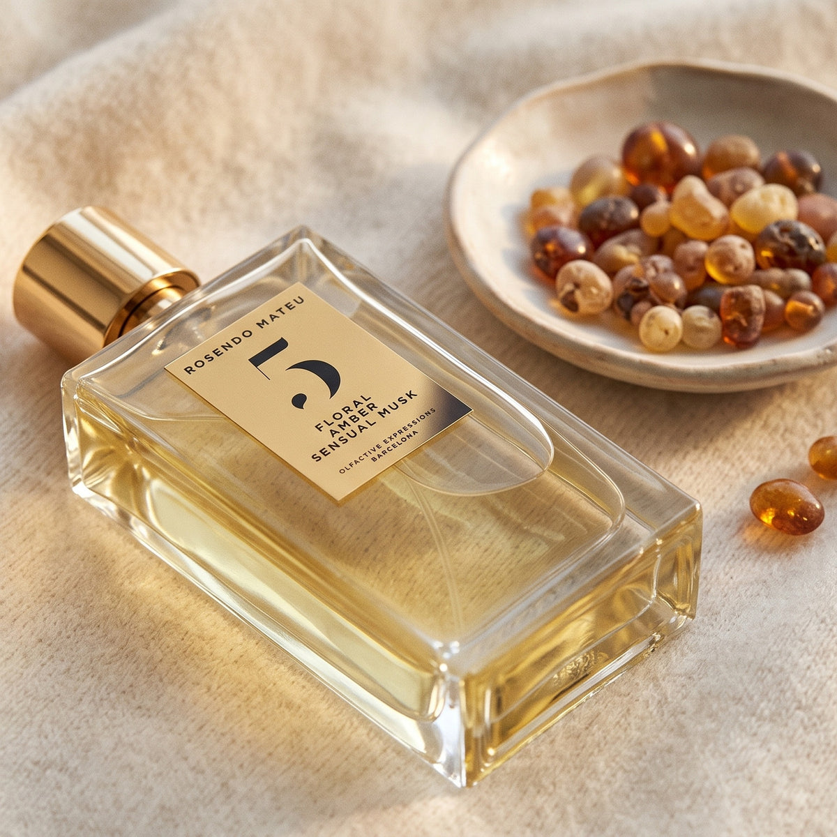 Rosendo Mateu No. 5 EDP on cream cashmere with amber resin beads in a small dish