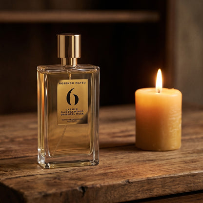 Rosendo Mateu No. 6 EDP on rosewood surface with a squat brass candle flickering nearby