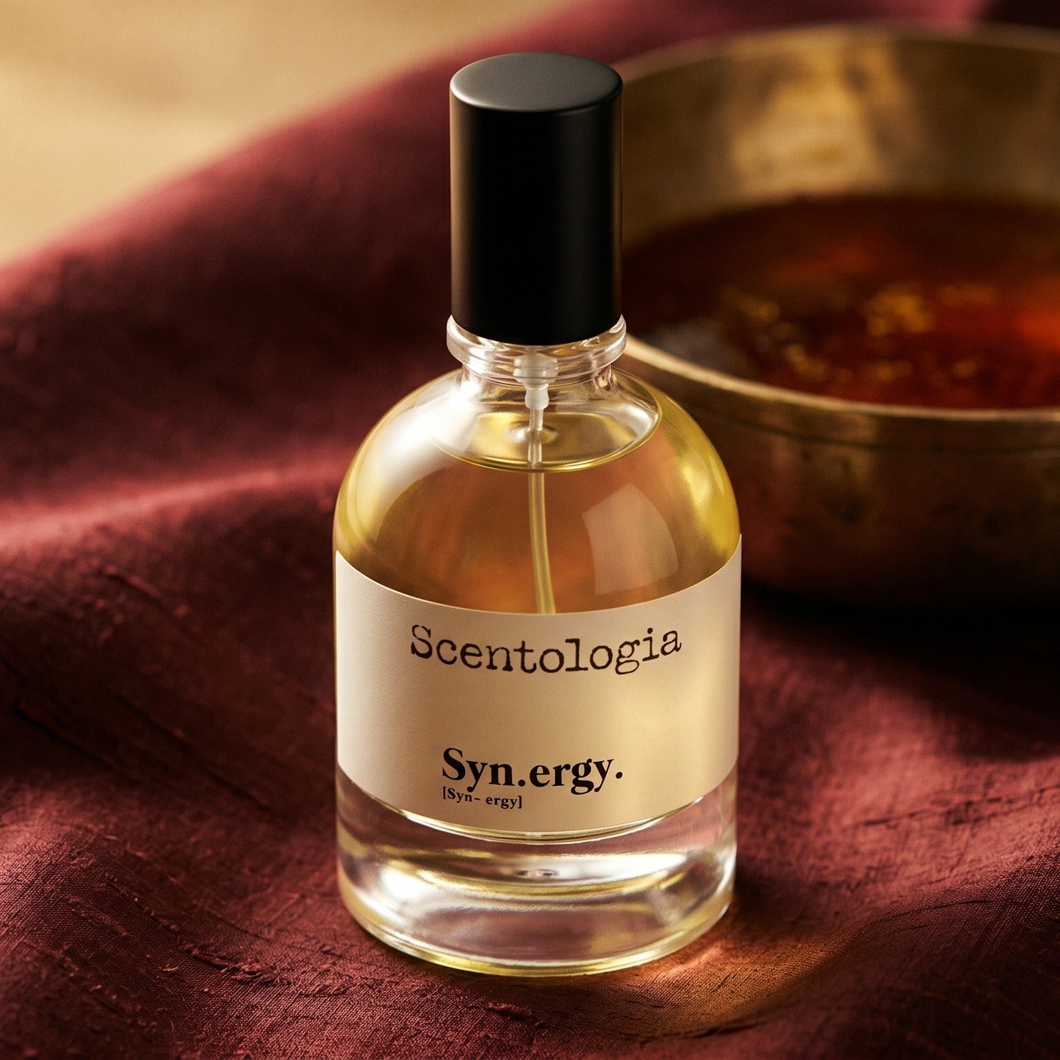 Scentologia Synergy EDP on russet silk with a matte brass bowl holding tonka and amber pieces