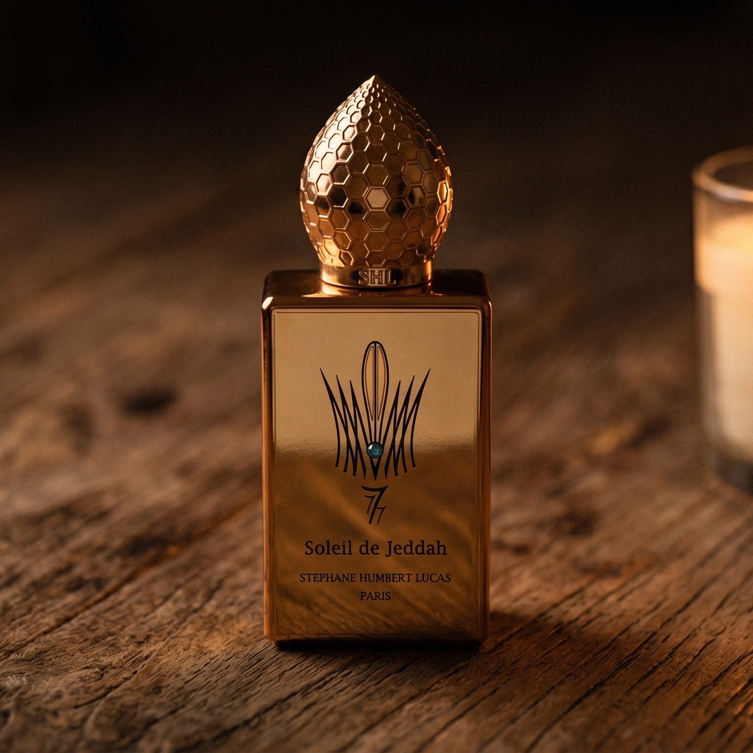 Stephane Humbert Lucas 777 Soleil de Jeddah Mango Kiss on rosewood surface with a squat brass candle flickering nearby