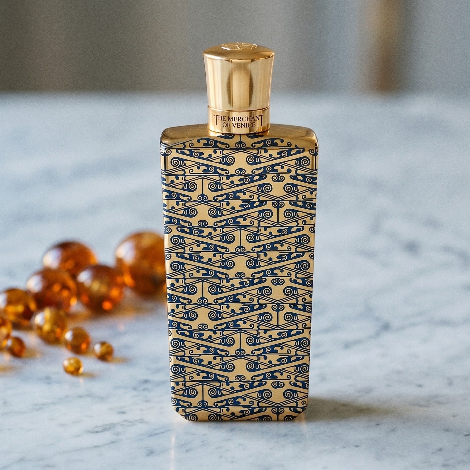 The Merchant of Venice Gold Regatta EDP on warm taupe marble with copal beads spilling from a small dish