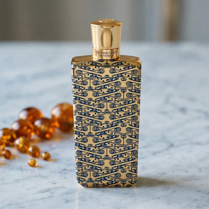 The Merchant of Venice Gold Regatta EDP on warm taupe marble with copal beads spilling from a small dish