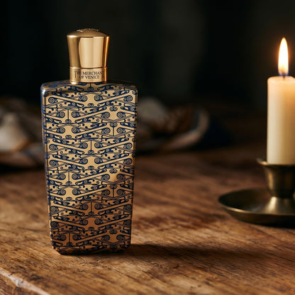 The Merchant of Venice Gold Regatta EDP on reclaimed oak surface with a glass hurricane lamp softly glowing